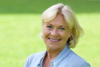 a woman with blonde hair smiling showcasing her new dental implants